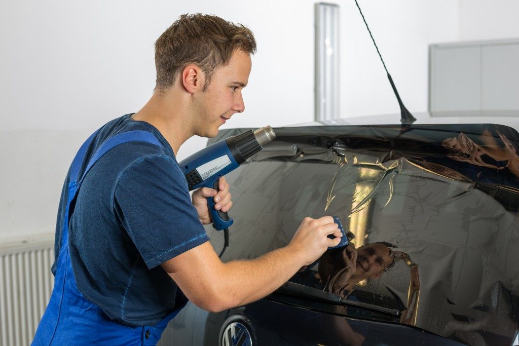 Auto mechanic tinting a car window