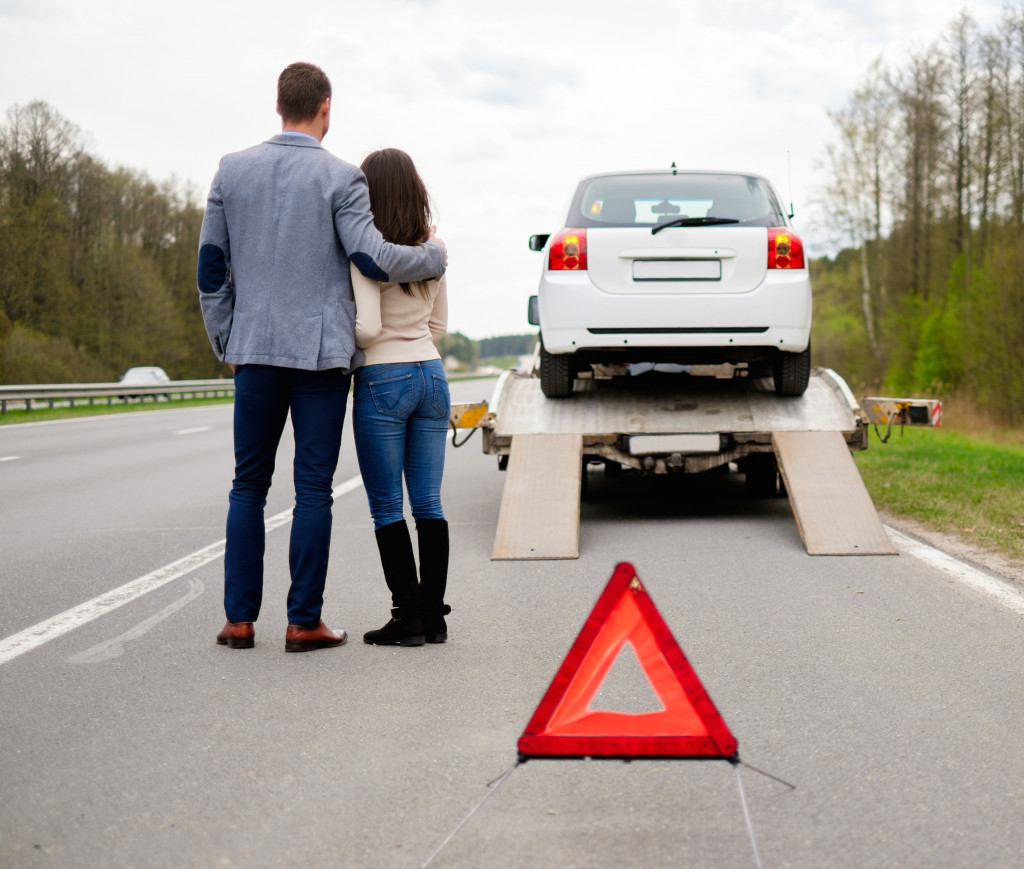 Couple near tow-truck picking up broken car