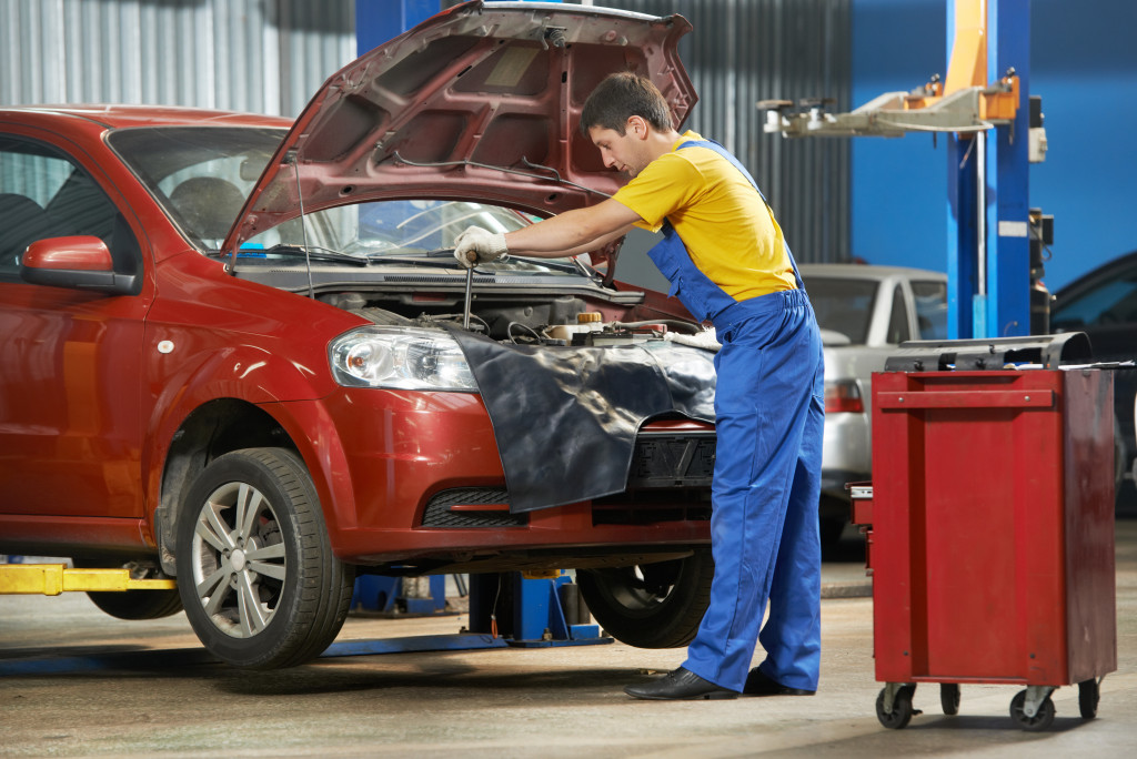 young auto mechanic tightening screw of a car engine