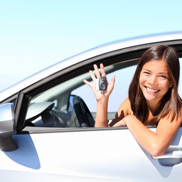 asian car driver holding car keys and smiling