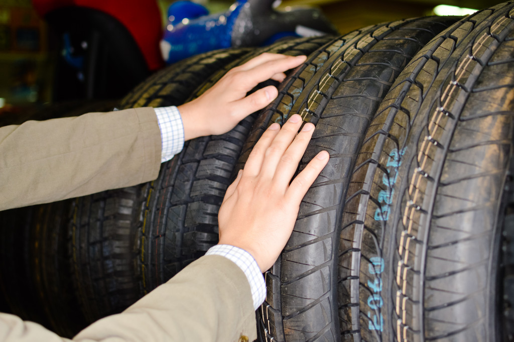 Hands choosing from various car tires